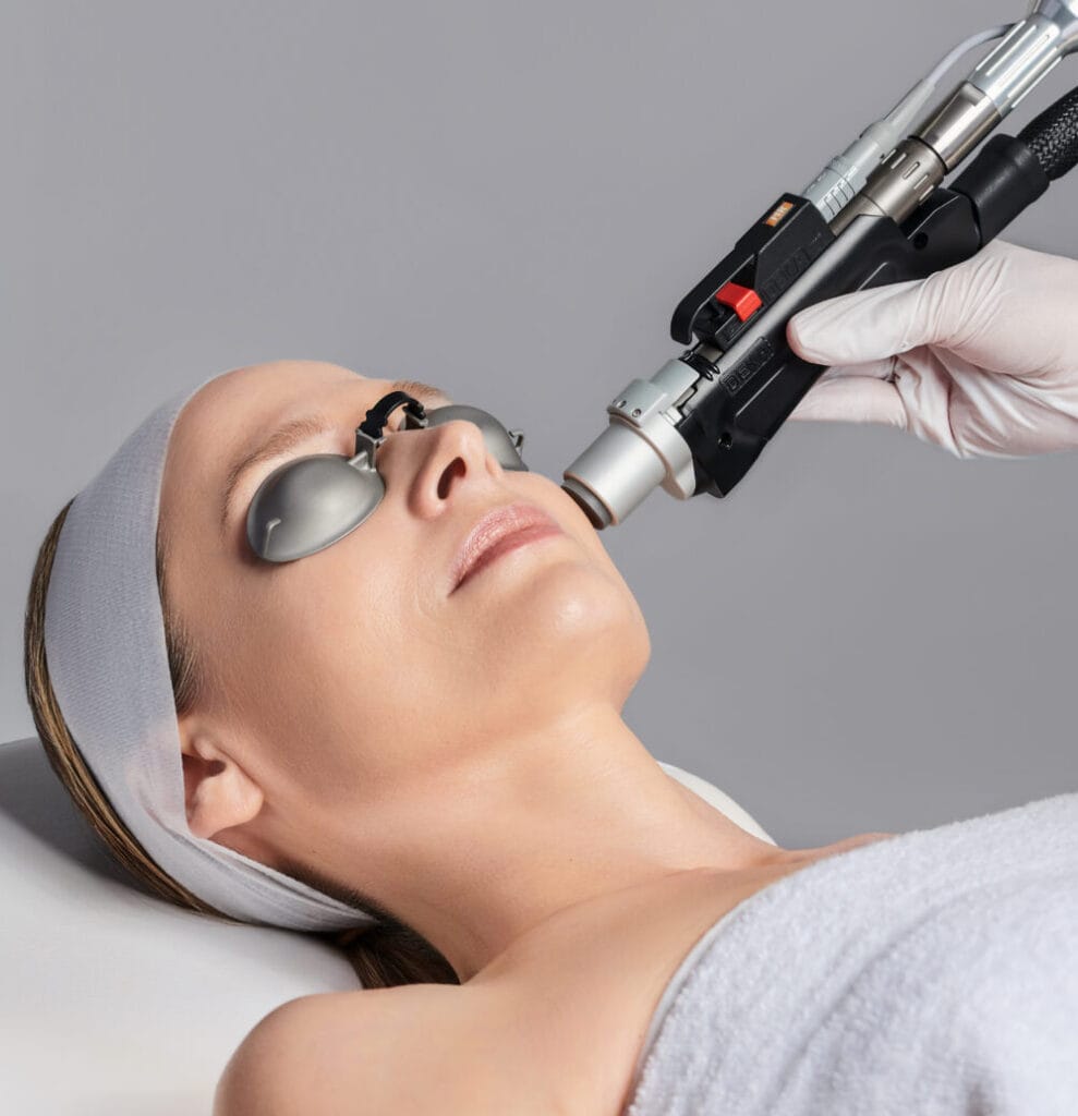 A woman is receiving a laser facial treatment at a spa.