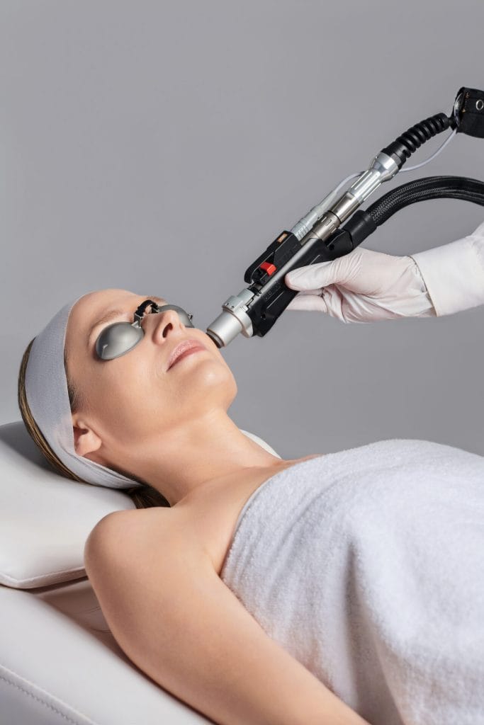 A woman is receiving a laser facial treatment at a spa.