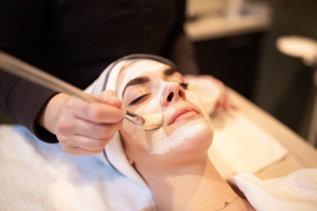 A woman receiving a facial massage at a spa.