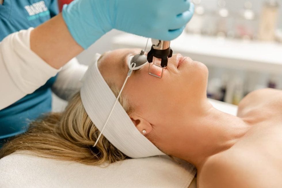 A woman receiving a facial skincare treatment at a beauty salon.
