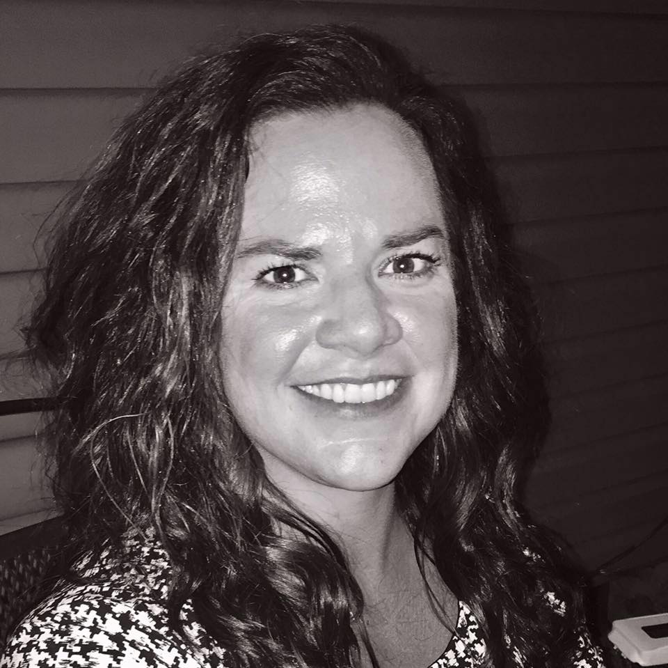 A black and white photo of a woman smiling with radiant skincare.