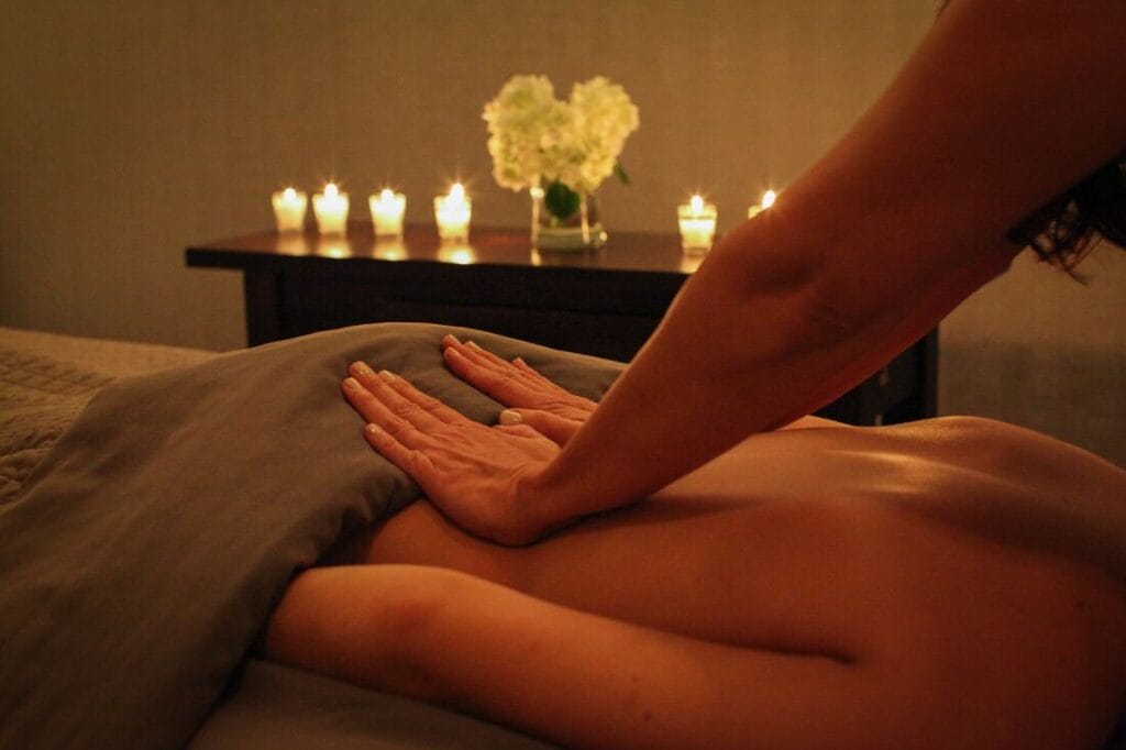 A woman receiving a skincare massage in a room with candles.