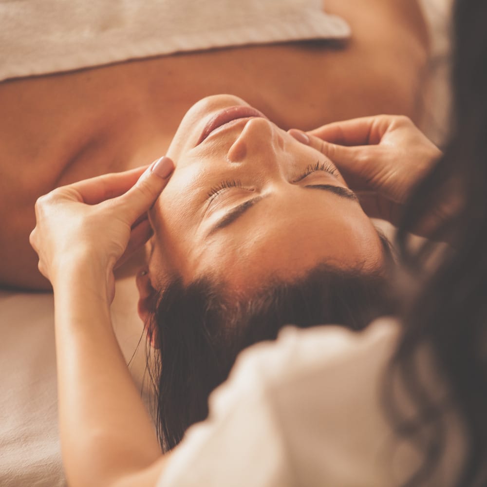A woman receiving a facial massage during a spa session.