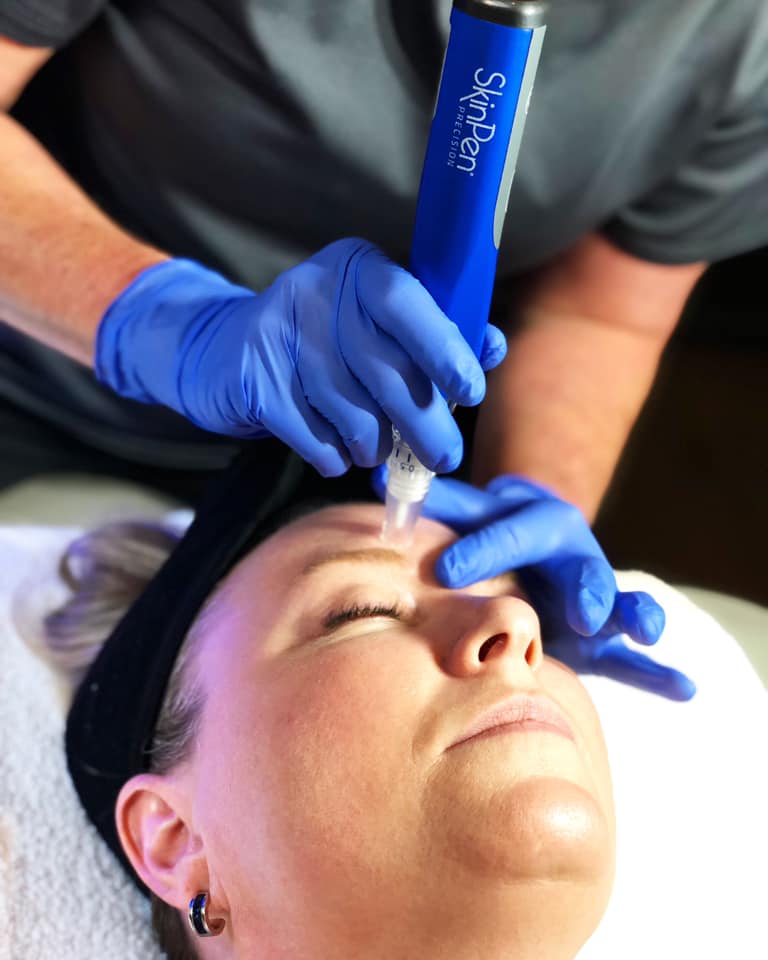 A woman receiving a facial massage with a blue light.