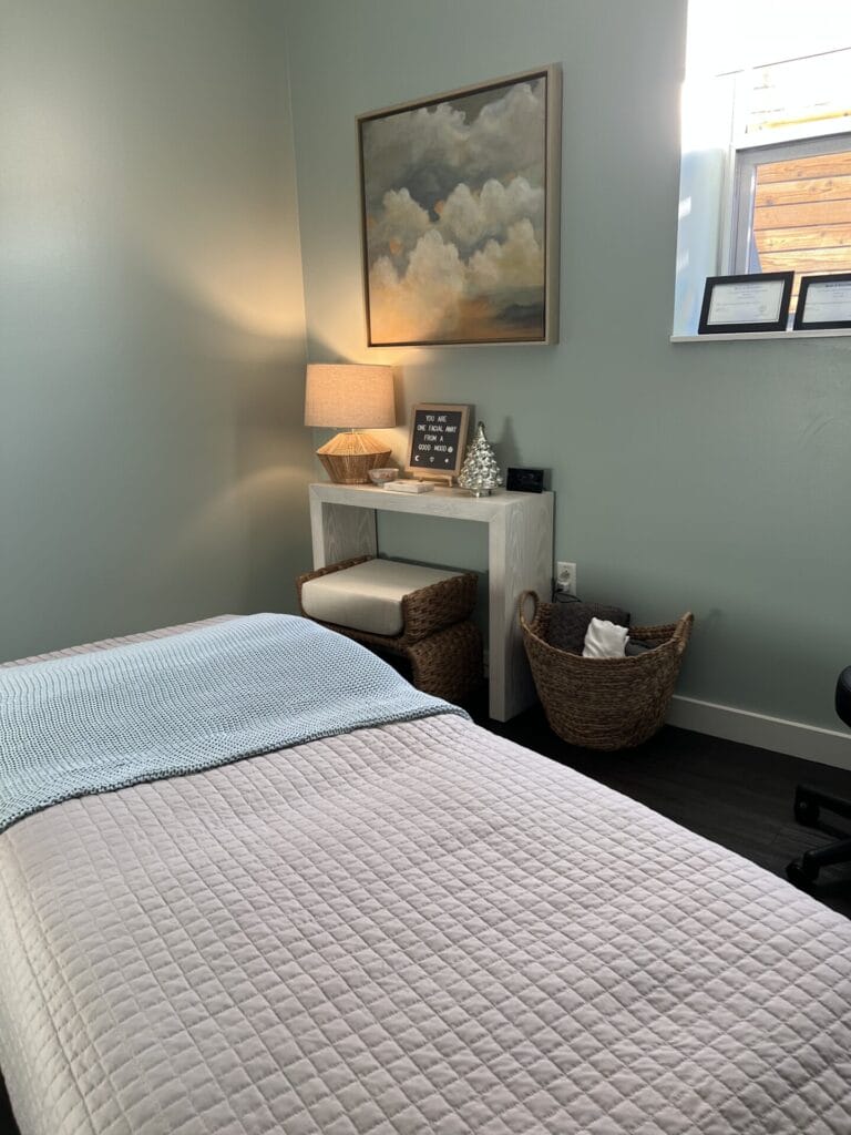 A spa room equipped with a massage bed and chair.