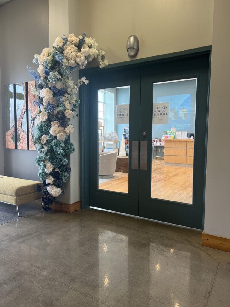 A floral arrangement adorns a green door at a spa.