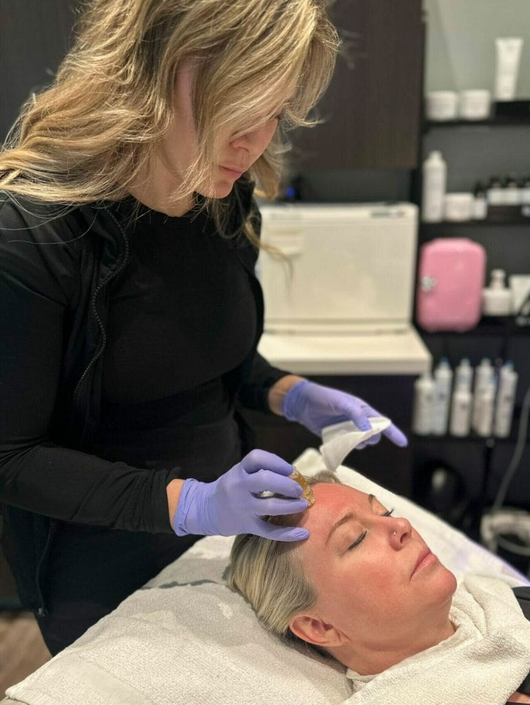 A woman getting an AQUAGOLD facial treatment at a beauty salon.