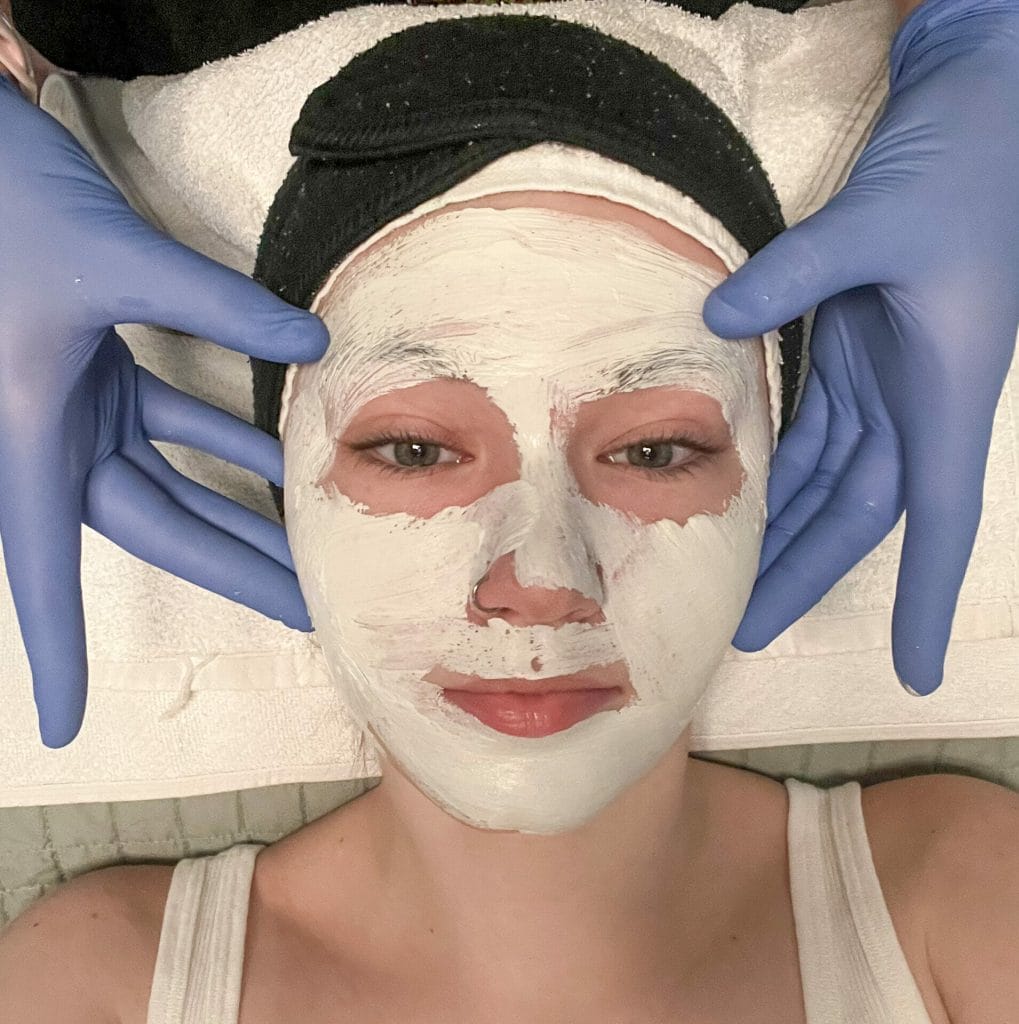 A woman receiving a skincare facial massage.