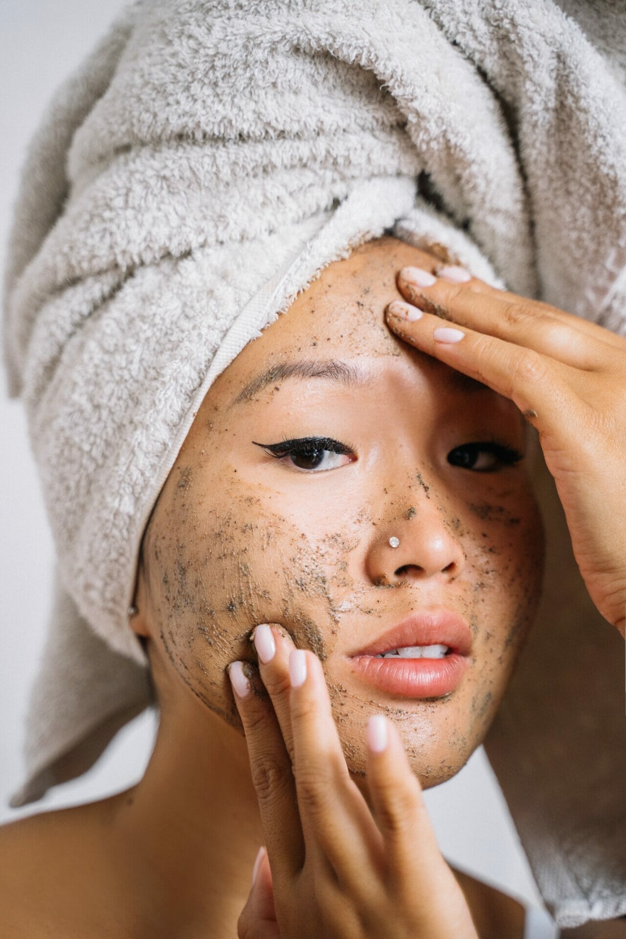 An Esthetician's Guide to Properly Exfoliating Your Skin: Woman applying mud-mask.