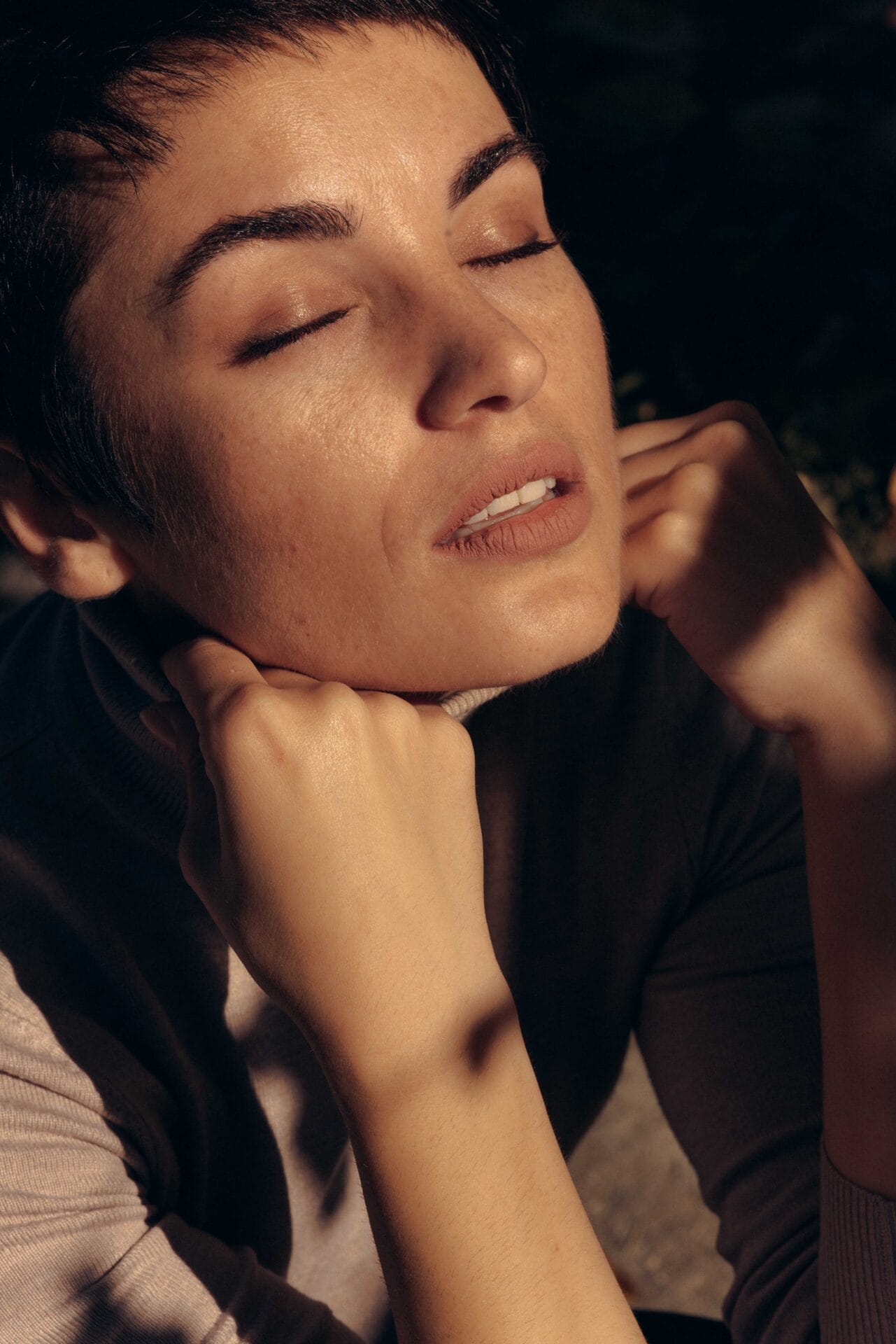 A woman posing with her eyes closed, showcasing the results of natural and tasteful use of cosmetic injectables to maintain a youthful appearance.