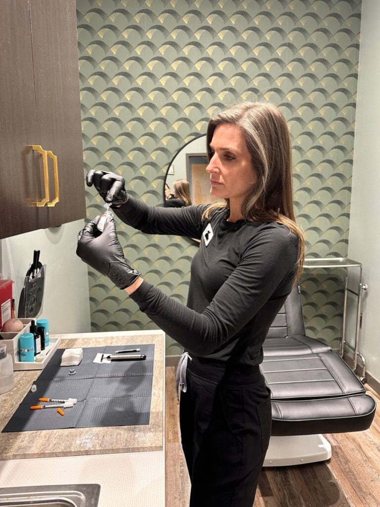 A woman putting on gloves in a bathroom.