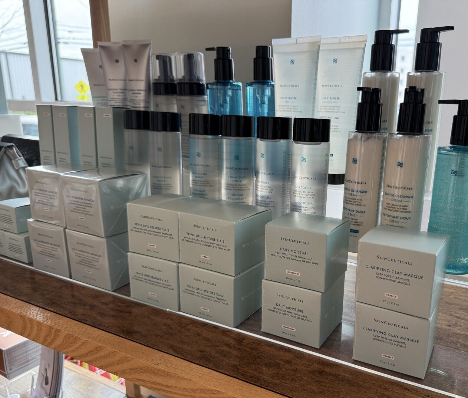 A festive display of skincare products, including elegant bottles and boxes, takes center stage on a shelf near the window at Center Medspa. Perfect for holiday shopping during the 12 Days of Christmas, it promises glowing skin for every merry occasion.