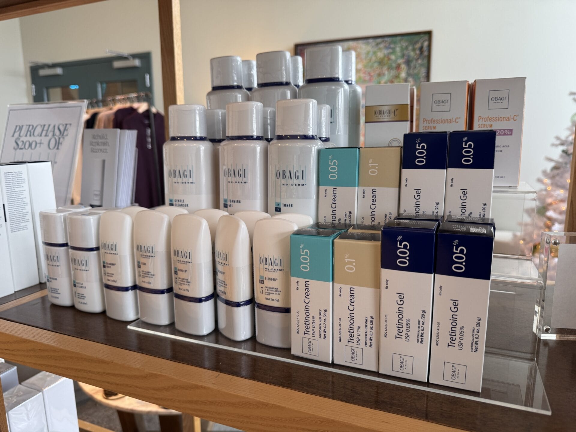 A festive display of skincare products on wooden shelves, perfect for holiday shopping, featuring bottles and boxes labeled Obagi and 0.05 Tretinoin Gel. Visit Center Medspa to find the ideal Christmas gift for your loved one's skincare routine.