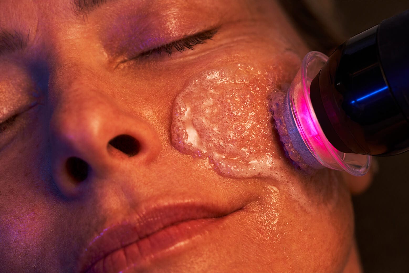 Close-up of a person's face receiving a rejuvenating skincare treatment at Center MedSpa with a device emitting red light, perfect for achieving that holiday glow just in time for Christmas.