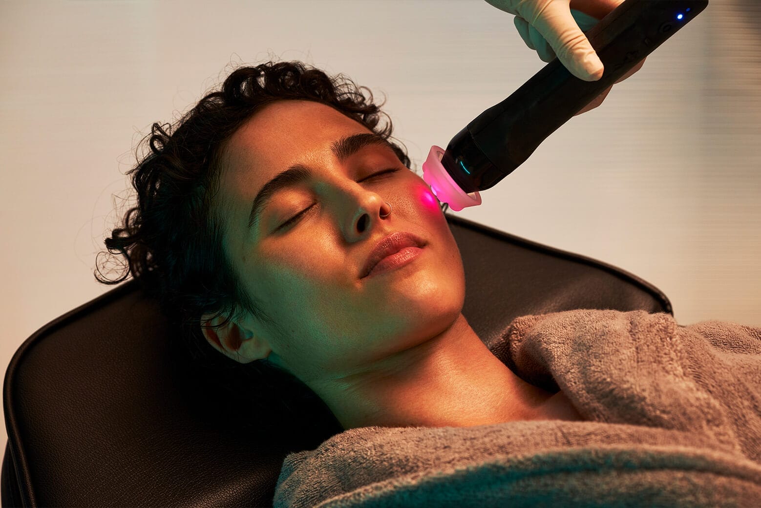 A person receives a rejuvenating facial treatment at Center MedSpa, lounging comfortably in a gray robe. The gentle hum of the cosmetic laser offers a soothing prelude to a radiant glow—just in time for Christmas celebrations.