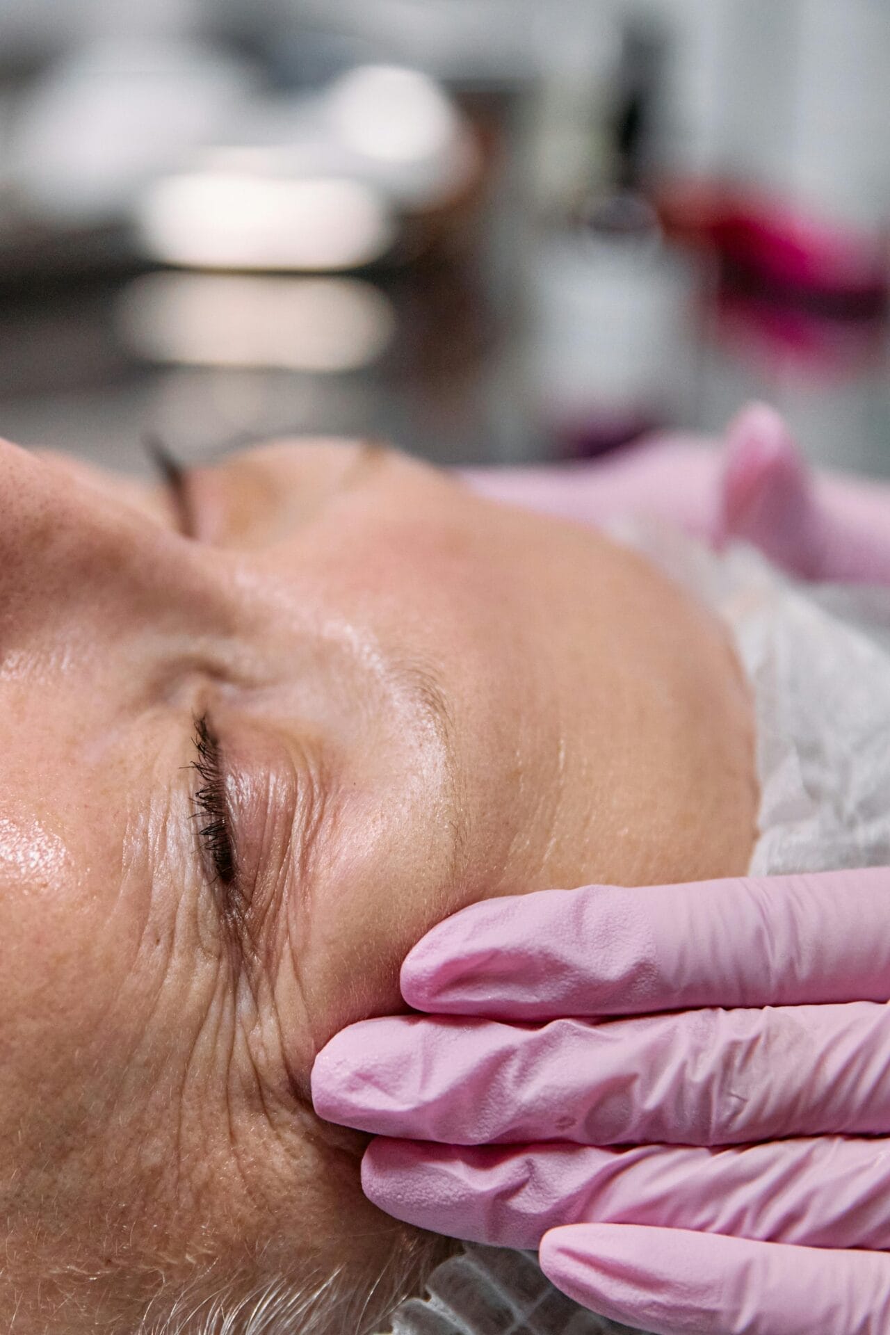 Close-up of a person receiving a rejuvenating facial treatment at Center MedSpa, with gloved hands gently pressing on the skin.