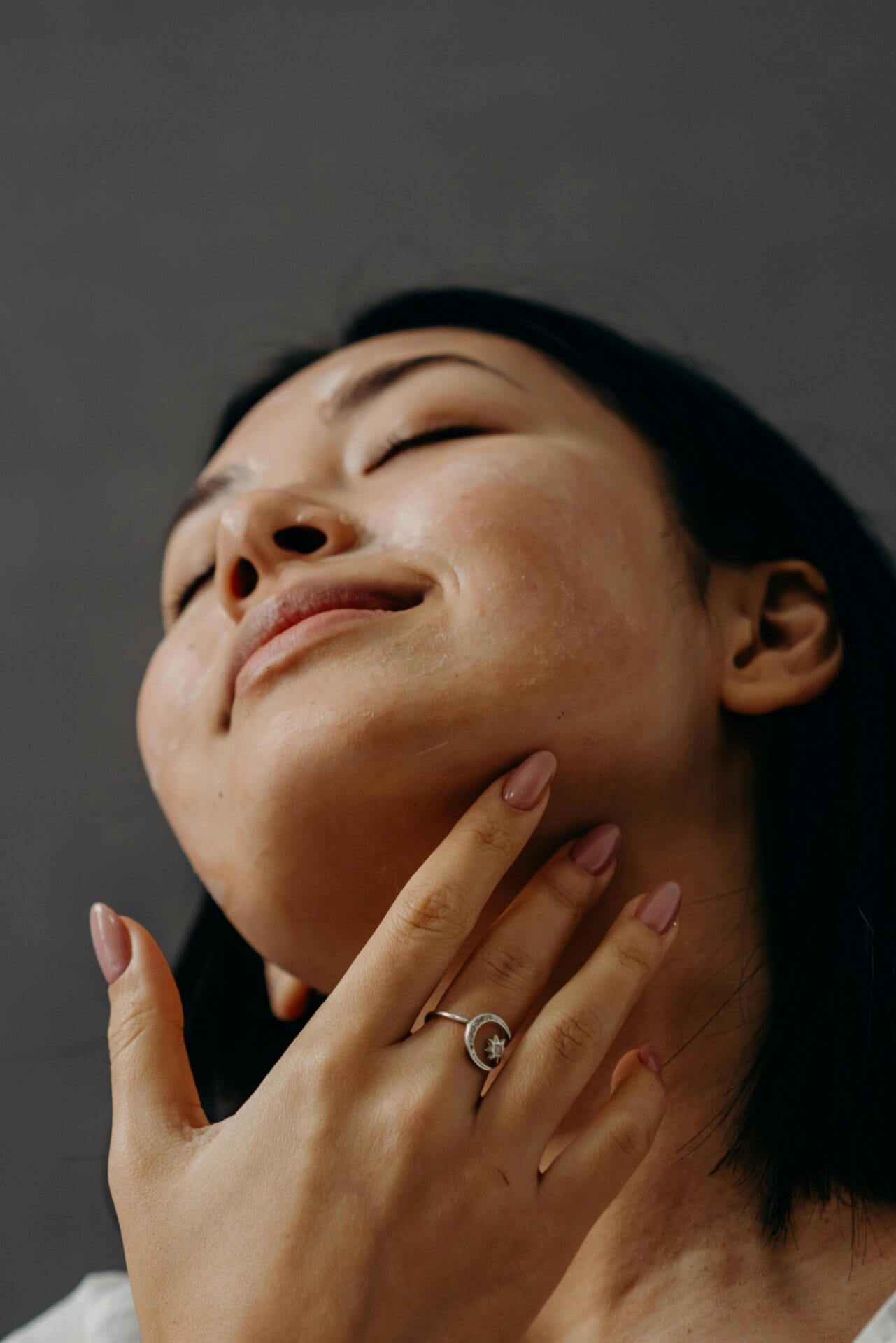 A person with closed eyes gently touching their face, highlighting a ring on their finger against a neutral background, evokes the serenity of treatments at Center MedSpa.